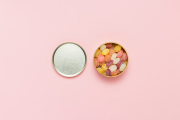 Multicolored lollipops in a round can on a gently pink backgroun