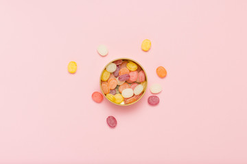 Multicolored lollipops in a round can on a gently pink backgroun