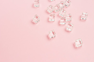 Ice cubes scattered on a light pink background. Flat lay, top vi