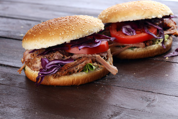 Pulled pork sandwiches with BBQ sauce, cabbage and tomato on table