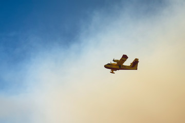 The firefighting plane comes out of the smoke of the fire smoke