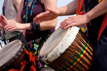 A man and a woman playing on colorful drums