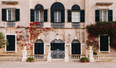 Ancient maltese house with red bougainvillea in the wall