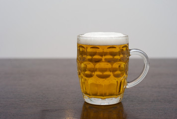 A Pint of Beer in a Dimpled Pint Glass on a Dark Wooden Table