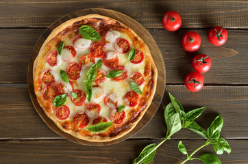 Pizza Margherita on a cutting board, fresh tomatoes and basil