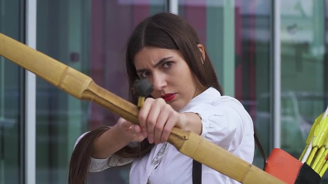 Beautiful girl in a shirt with a bow aiming