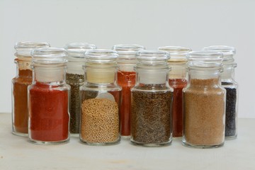 9 glass jars filled with colourful spices and dried herbs.
