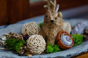 Floral composition with seaweed, rattan balls and straw deer on a plate