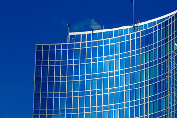 Glass facade of modern building reflecting blue sky
