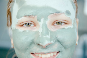  cute young girl with a cosmetic mask, clay on the face. skin care in the winter.