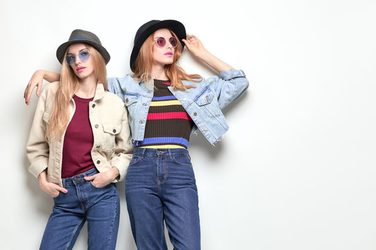 Two Girl posing in Studio. Young Playful Sisters Twins Having Fun, Trendy Hairstyle, Fashion Stylish jeans, hat. Full-length portrait. Cheerful Blond Redhead Woman in denim Autumn Outfit