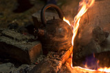 The kettle is heated on a fire at night outdoor