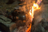 The kettle is heated on a fire at night outdoor