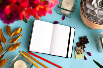 Styled mockup with blank notepad and pink flower, gold leaf, candle, pen on color background. Flat lay, top view, copy space © iryna_mishyna