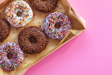 Delicious glazed donuts in box on pink surface