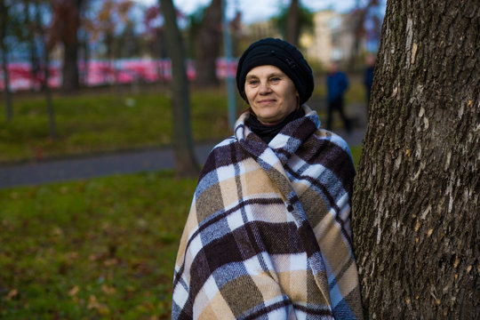Attractive middle aged woman covered with blanket walk in autumn park