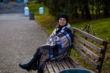 Attractive middle aged woman covered with blanket walk in autumn park