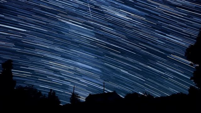 Long luminous tracks of stars in the sky - Starry night sky in timelapse - ISS is appearing at 2"17 - Looking to southwest from Western Europe above an isolated house in countryside.
