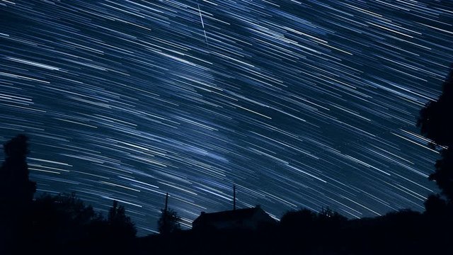 Stars create trails in the sky and seem falling as meteors - Starry night sky in timelapse - ISS is appearing at 2"17 - Looking to southwest from western Europe above an isolated house in countryside.