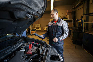 Mechanic using booster cables to start-up a car engine