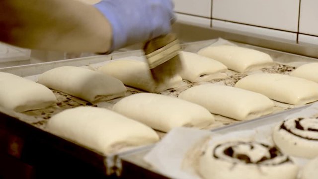 Cook confectioner lubricates the buns with whipped chicken eggs before baking.