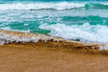 Olas del mar sobre la arena de la playa en la costa del Mediterráneo una mañana de verano con olas suaves rompiendo en la orilla