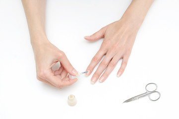 The girl makes a manicure beige lacquer. White background.