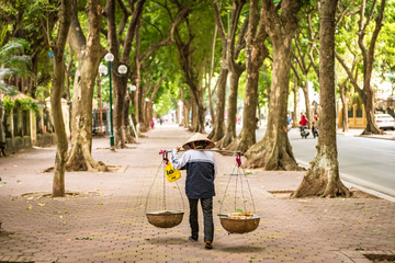 Mit Reishut und Schultertrage unterwegs auf Hanoi's schönster Baumallee