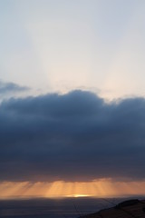 Fototapeta na wymiar Raggi di sole tra nuvole e mare al tramonto