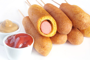 Corn dogs with ketchup and mustard on white background

