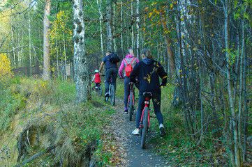 Naklejka premium Family rides a bike in the autumn forest.