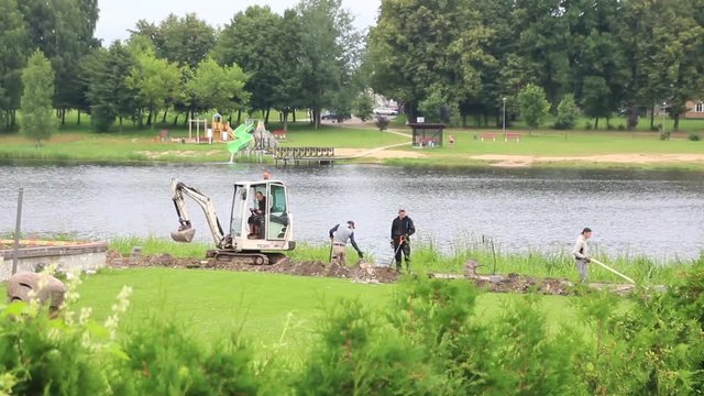 Mini excavator is working on the bank of the river. Time lapse