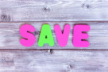 Message save made of colorful letters on vintage rustic wooden background