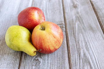 Autumn delicious apples and pear close up on wooden background