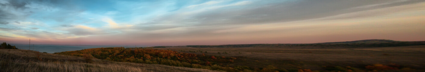 Naklejka na ściany i meble Panorama of hilly terrain with autumn forest near the Volga at sunset