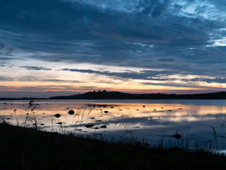 Shallow water and land with strong contrast just past sunset. Clouds reflecting from the still water surface.