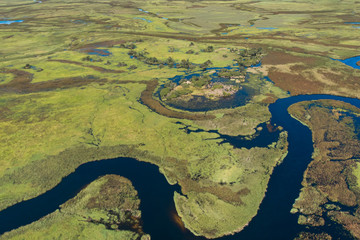 An aerial view capturing the swirling patterns of lush vegetation, meander river paths and land in the Okavango Delta, Botswana
