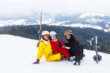 Fototapeta na wymiar Family ski vacation, family sitting on the top of mountain slope with ski