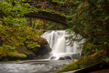 Waterfall in Whatcom Falls Park. A beautiful waterfall runs through this 241-acre park located in a rainforest environment with fir, maple and cedar trees. Autumn has arrived with colorful leaves. 