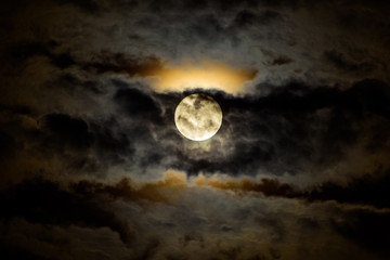 Naklejka na ściany i meble Full moon ascending behind dark clouds