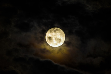 Full Moon Rising Behind Dark Clouds