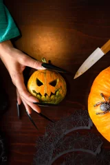 Foto op Plexiglas Photo of man's hands with pumpkin jack, knife sitting at wooden table © nuclear_lily