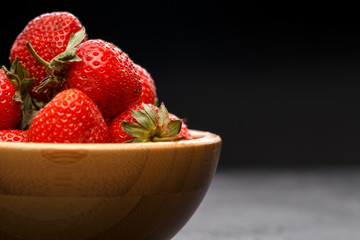 Photo close-up of ripe strawberry in wooden cup on black background