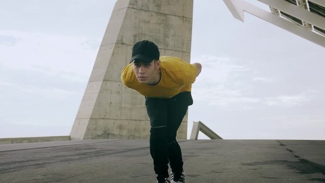 Epic Portrait and close upt of a Young Attractive Trendy Man skateboarding fast under a solar panel on a morning sunny day with an urban city background in slow motion