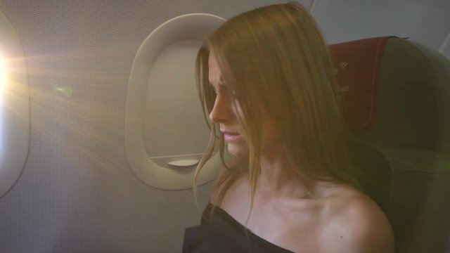 Young woman feels great fear in the airplane. Gimbal shot. 4K.