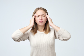 Stressed beautiful woman touching temples and thinking hard. Young lady having headache