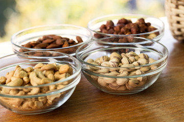 Assortment of mixed nuts and wicker basket on wood table background