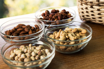 Assortment of mixed nuts and wicker basket on wood table background
