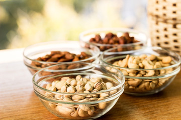 Assortment of mixed nuts and wicker basket on wood table background