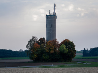 Image of big chminey with anntenas surrounded by colorful autumn trees